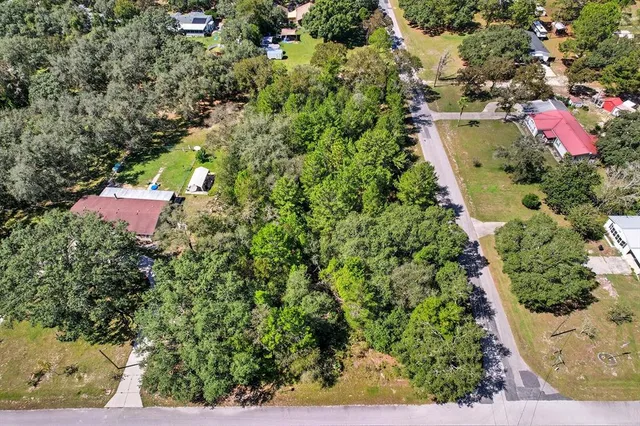 an aerial view of residential house with outdoor space and trees all around