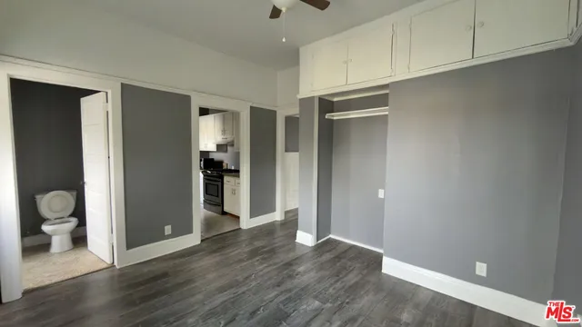 a view of an empty room with wooden floor and a bathroom