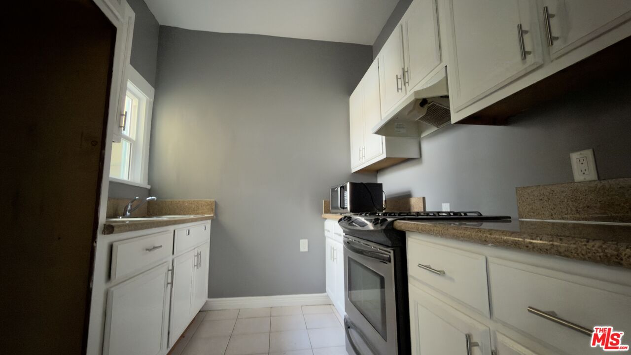 1820 South Highland Avenue, Unit 1820 Los Angeles, CA 90019 - Photo 8 of 11 a kitchen with granite countertop a sink a stove and cabinets