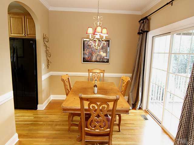 Spacious dining room with elegant chandelier, crown molding, and chair rail.  When the sliding glass door is open, it extends the living space out onto the screened porch.