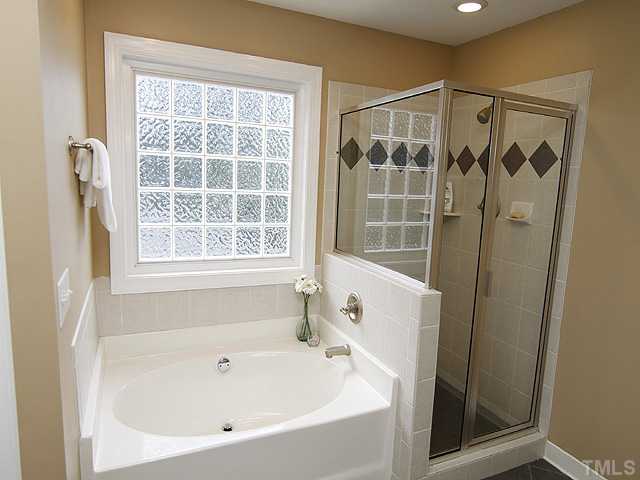 131 Forbes Road Wake Forest, NC 27587 - Photo 9 of 20 Relaxing spa tub with tile surround and fully-tiled shower with glass doors.