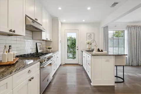 a kitchen with white cabinets stainless steel appliances and a window