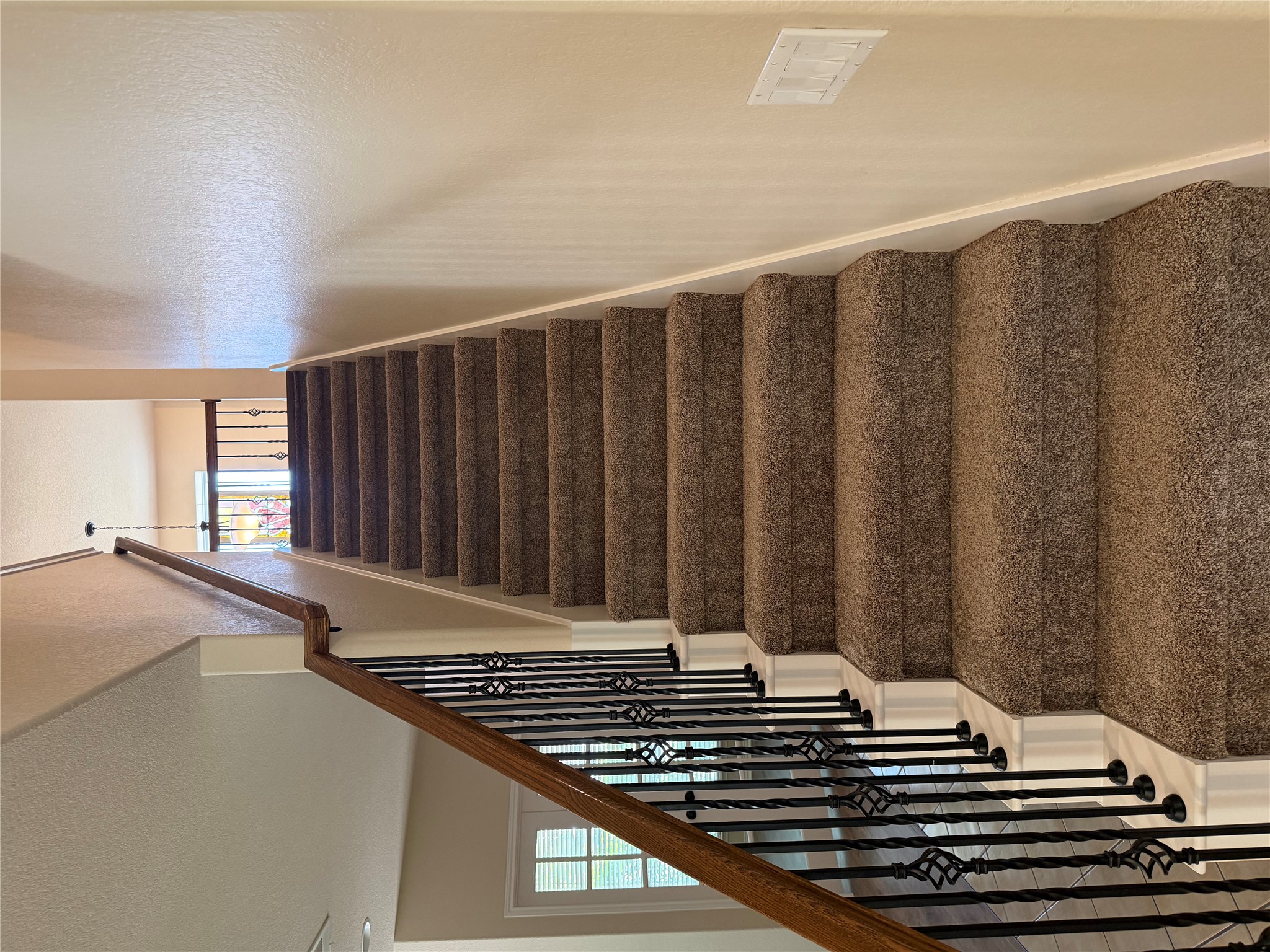 3021 Grand Mission Way Pflugerville, TX 78660 - Photo 20 of 31 A grand carpeted staircase with ornate iron balusters leads to an upper landing.