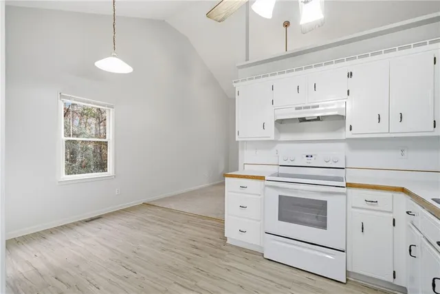 a kitchen with stainless steel appliances white cabinets and a wooden floors