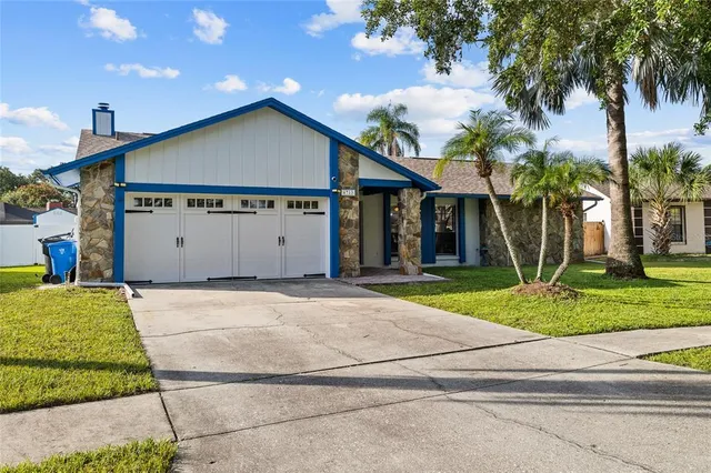a view of a house with a yard and palm trees