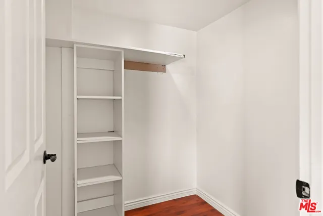 a view of a hallway with wooden floor and a bathroom