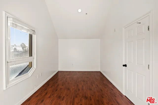 a view of an empty room with wooden floor and closet