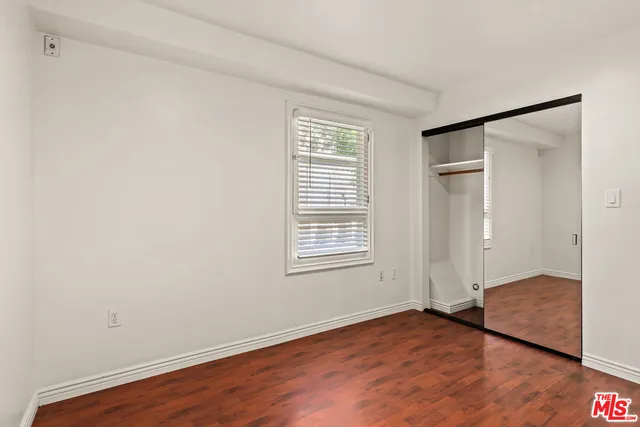 a view of an empty room with wooden floor and window