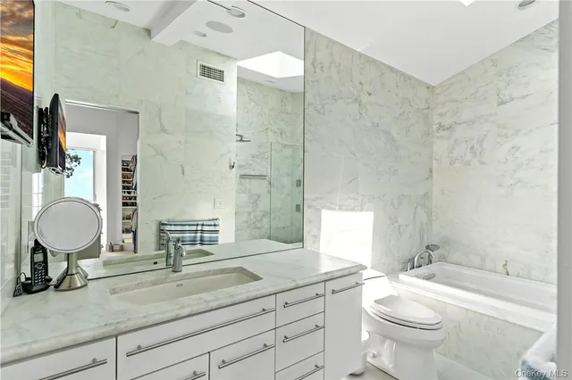 a bathroom with a granite countertop toilet a sink and a mirror
