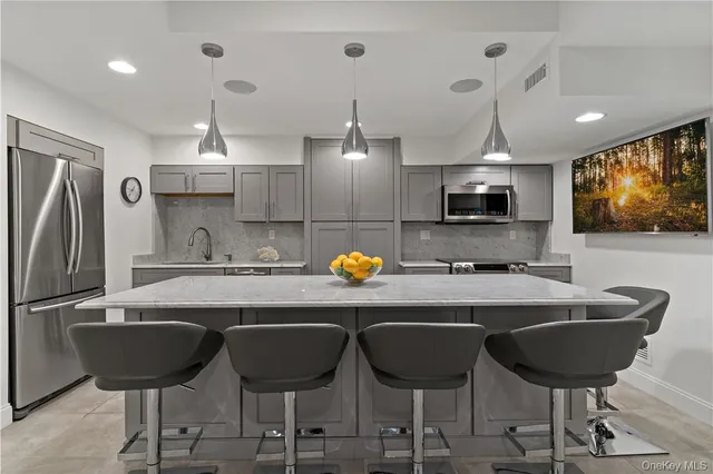 a kitchen with stainless steel appliances granite countertop a sink a stove a refrigerator and chairs