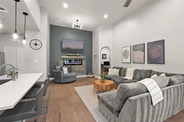 a living room with furniture kitchen view and a wooden floor