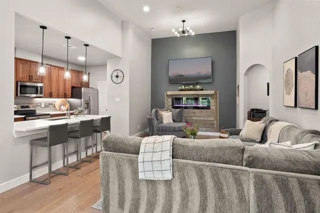 a living room with furniture kitchen view and a wooden floor