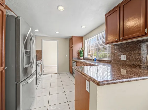 a kitchen with stainless steel appliances granite countertop a refrigerator a sink and a stove