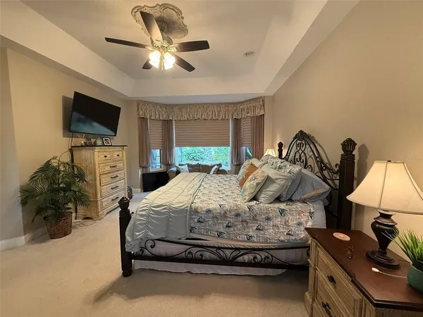 a bedroom with a bed a flat screen tv and a chandelier