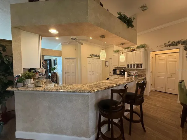 a kitchen with kitchen island granite countertop wooden cabinets and refrigerator