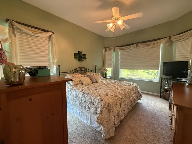 a bedroom with a bed a flat screen tv and a large window