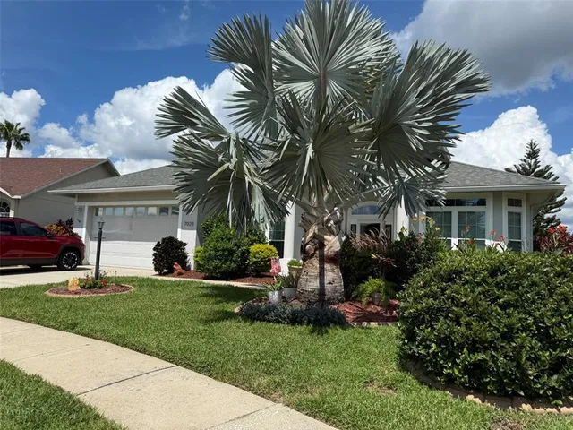 a front view of a house with a garden and palm trees