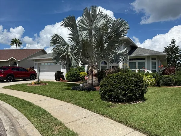 a front view of a house with a garden and trees