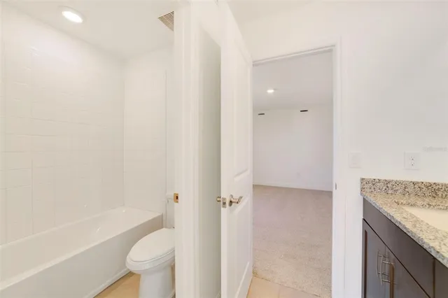 a bathroom with a granite countertop bathtub shower sink vanity and toilet