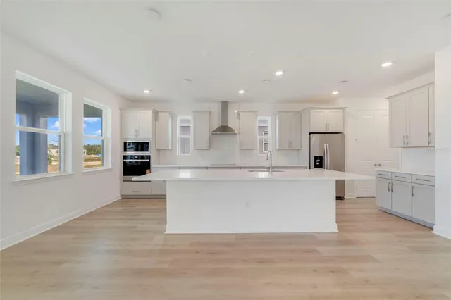 a large kitchen with kitchen island a sink a center island stainless steel appliances and a cabinets