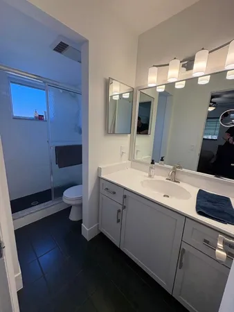 a spacious bathroom with a double vanity sink a large mirror and toilet