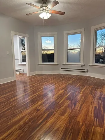 a view of an empty room with wooden floor and a window
