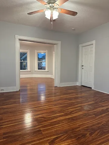 an empty room with wooden floor chandelier and windows