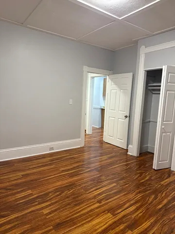 an empty room with wooden floor and refrigerator
