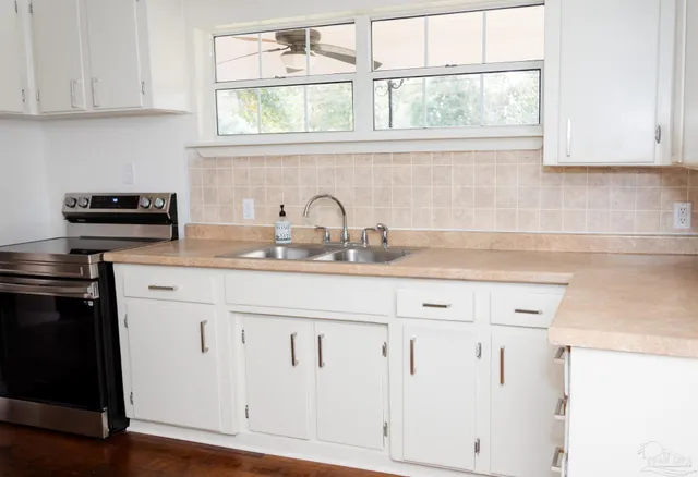 a kitchen with granite countertop white cabinets and a window