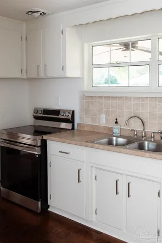 a kitchen with granite countertop white cabinets and a stove