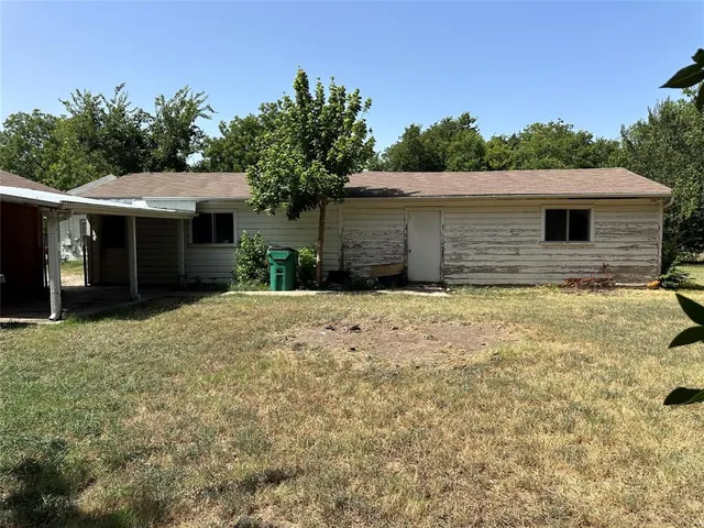 a front view of house with yard and trees in the background