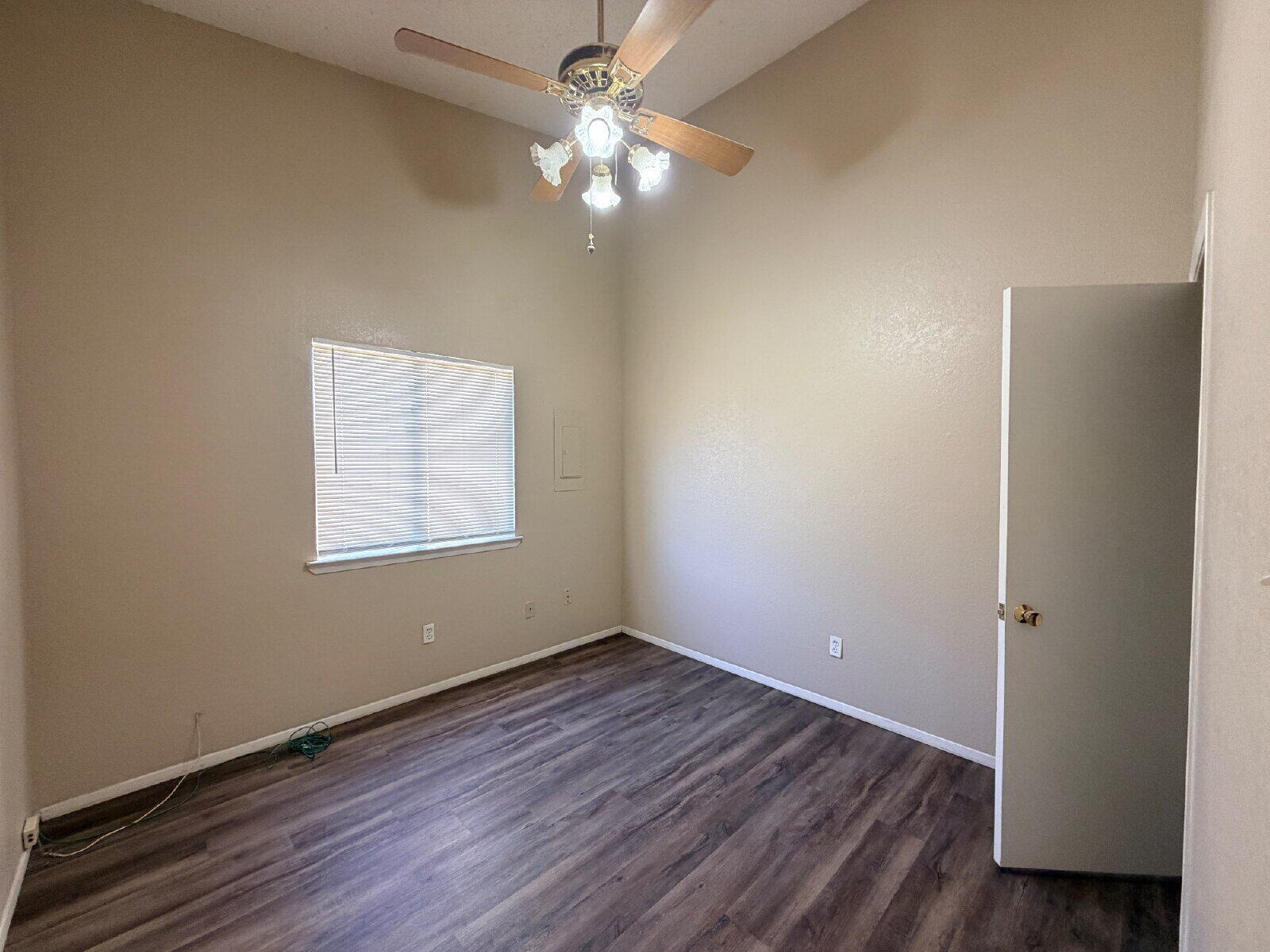 129 North Troy Avenue, Unit B Lubbock, TX 79416 - Photo 4 of 9 an empty room with wooden floor chandelier fan and windows