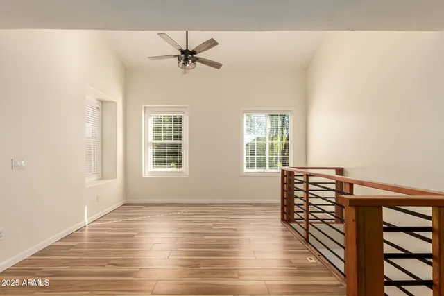 a view of empty room with wooden floor and fan