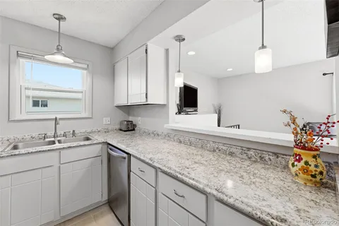 a kitchen with granite countertop a refrigerator stove and sink