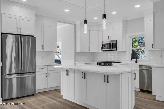 a large white kitchen with a large island oven a sink stainless steel appliances and cabinets