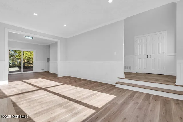 a view of an empty room with wooden floor and white wall