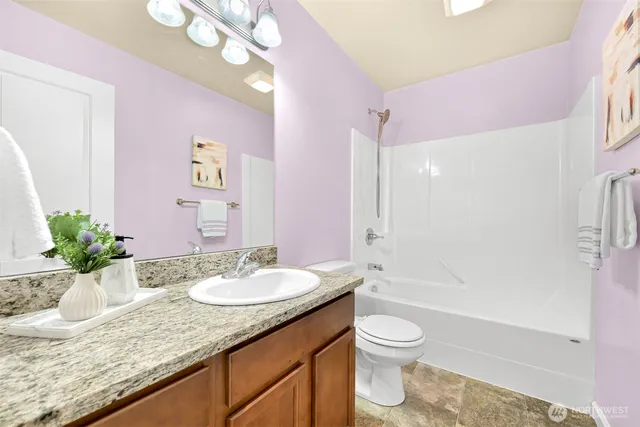 a bathroom with a granite countertop sink a toilet and shower