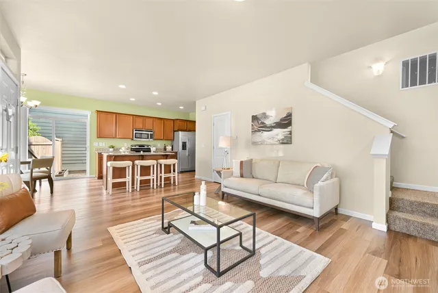 a living room with furniture a wooden floor and kitchen view