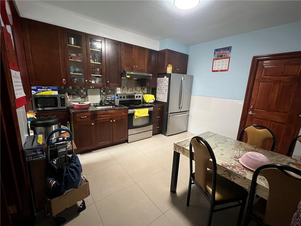 6710 13th Avenue Brooklyn, NY 11219 - Photo 4 of 9 a kitchen with stainless steel appliances a stove a refrigerator a sink a dining table and chairs