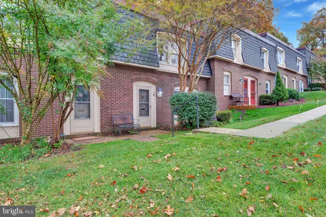 a view of a yard in front of a brick house with large windows