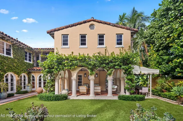 a view of a white house with a tree and flower plants