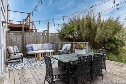 a roof deck with a dining table and chairs with potted plants