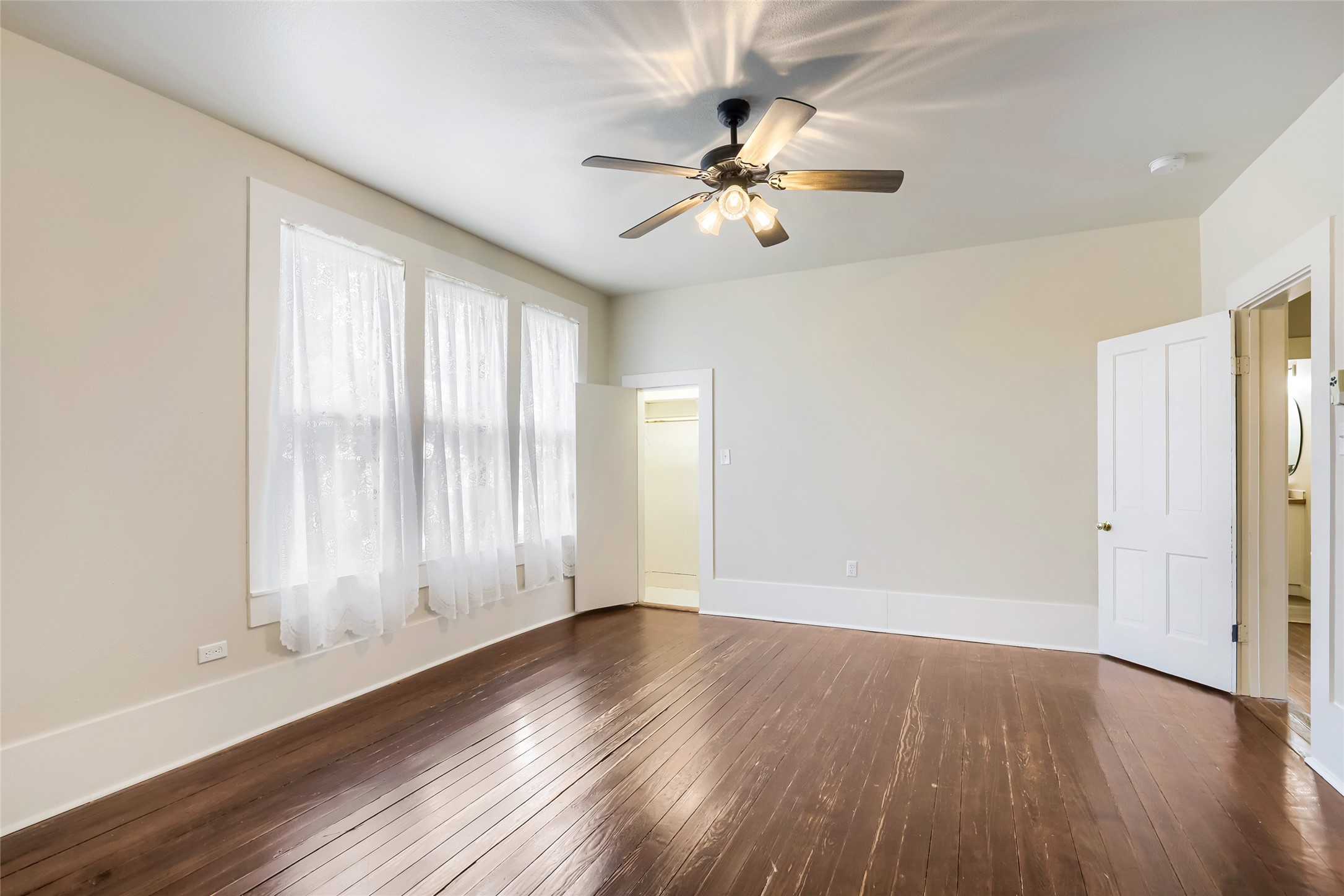 208 North Ave B Elgin, TX 78621 - Photo 23 of 29 an empty room with wooden floor fan and windows