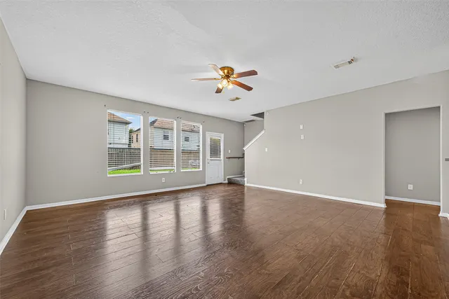 a view of an empty room with a kitchen and wooden floor