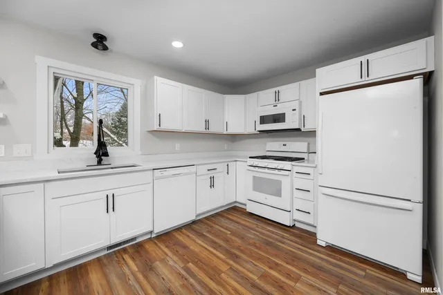 a kitchen with granite countertop white cabinets and white appliances