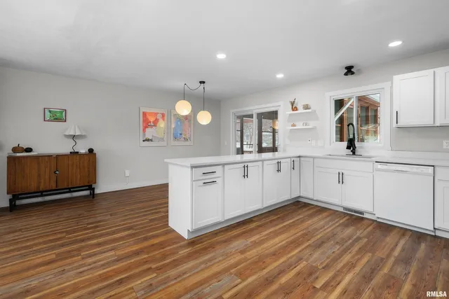 a large kitchen with wooden floors and white cabinets