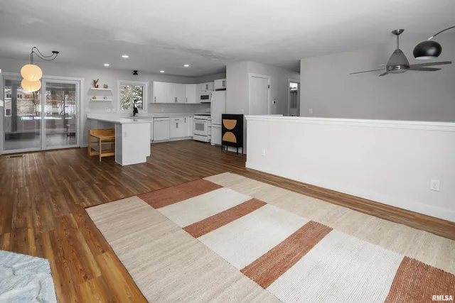a living room with stainless steel appliances kitchen island a rug and a kitchen view