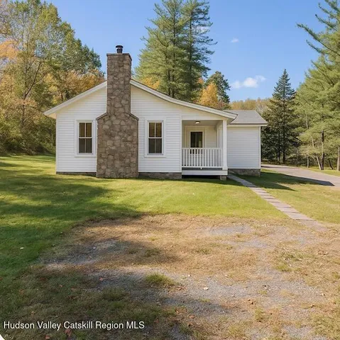 a view of a yard in front of a house with a large tree