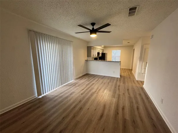 a view of a big room with wooden floor a ceiling fan and windows