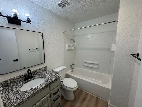 a bathroom with a granite countertop sink toilet a mirror and shower